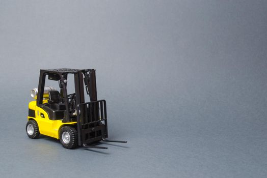 Yellow forklift truck on gray background. Warehouse equipment, vehicle. Logistics and transport infrastructure, industry and agriculture. Unloading, transportation, sorting, loading cargo.