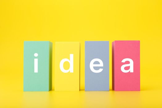 Concept of idea, creativity, start up or brainstorming. Single word idea written on multicolored rectangles in a row on bright yellow background