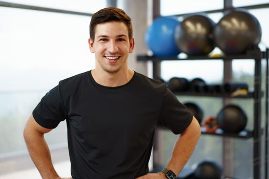 Portrait of a young handsome fitness trainer in a gym, close up