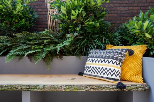 Cozy seating, Wooden sofa with colorful pillows in cozy garden seat, green plants and modern decoration bright colors