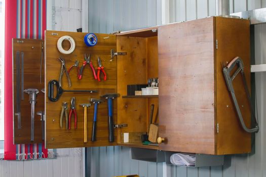 Open wooden cupboard with working tools, close up