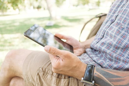 Young man using digital tablet in summer park.