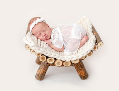 Beautiful newborn sleeping on wooden pedestal