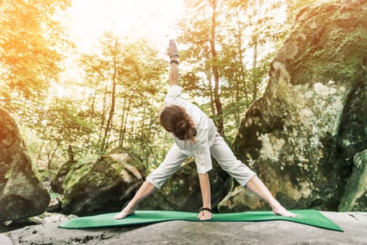Young woman wearing in white clothing exercising on yoga mat in forest, healthy lifestyle outdoor.