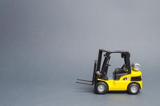 Yellow forklift truck side view on gray background. Warehouse equipment, vehicle. Unloading, transportation, sorting, loading cargo. Logistics and transport infrastructure, industry and agriculture