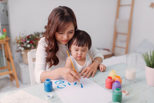 Little girl painting with her mother at home