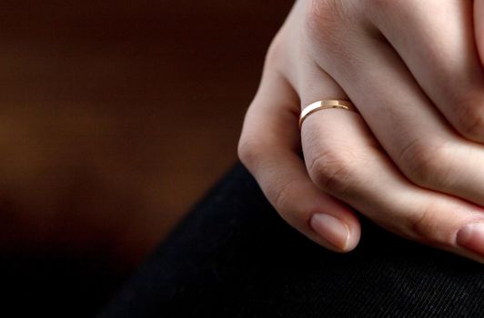 Closeup shot of a person s hand with a wedding ring on a brown surface. High quality photo