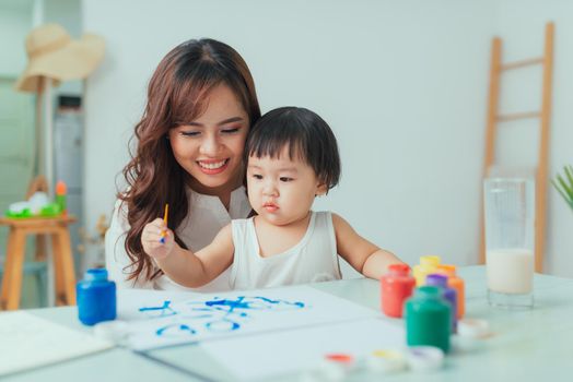 Young mother looking how her daughter drawing a picture