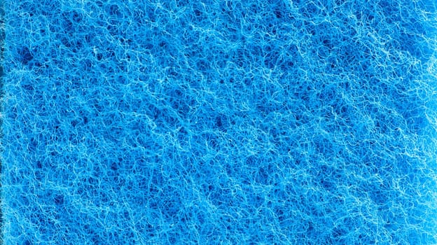 Background in the form of a porous structure in blue. Macro sponge. Close up blue sponge surface for textured background. copy space