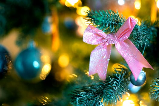 Christmas background with beautiful pink bow on green branch of decorated Christmas tree and bokeh lights background, copy space, Holiday,xmas concept space for text