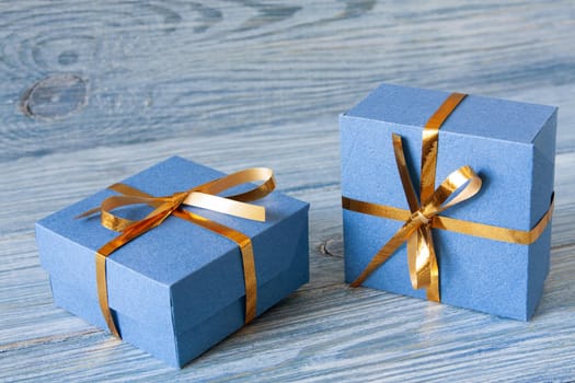 Blue gift boxes with golden ribbons on a blue wooden background for Christmas, New Year, birthday or Valentine's Day