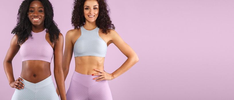 Attractive excited fitness girls in sportwear jumping of joy isolated over light background