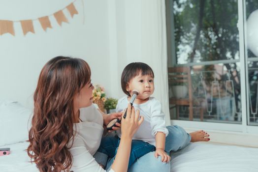 Pretty mother applying blush on her kid little girl cheek