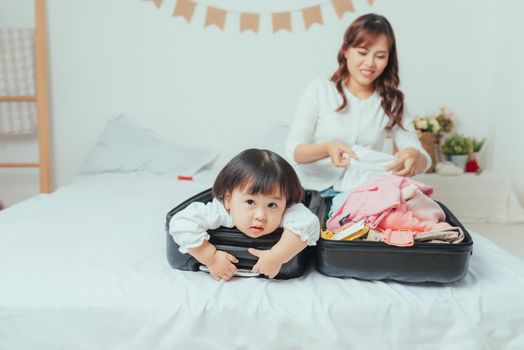 mother and daughter in a hat and packing suitcase, holidays in quarantine