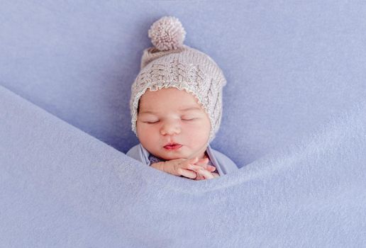 Adorable sleeping newborn covered with purple blanket