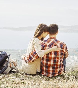 Young couple in love resting in the mountains above the sea bay.