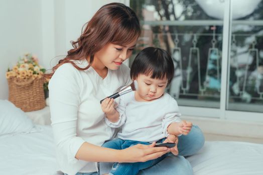 Beautiful young woman and little girl putting make up on