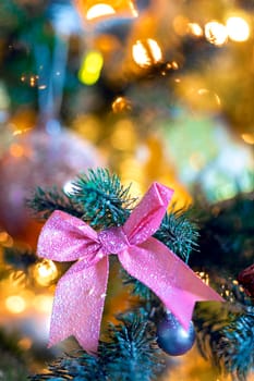 Christmas background with beautiful pink bow on green branch of decorated Christmas tree and bokeh lights background, copy space, Holiday,xmas concept space for text
