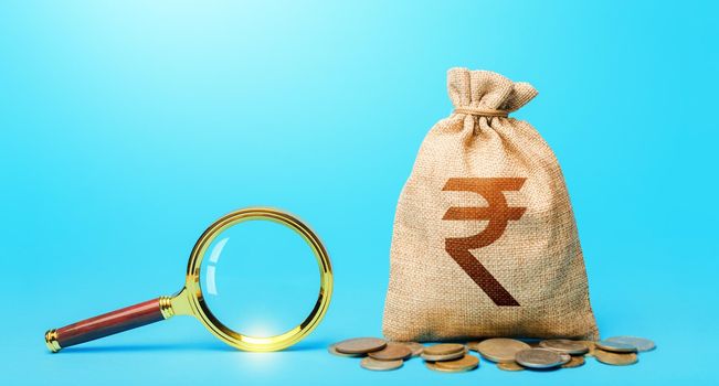 Indian rupee money bag and magnifying glass. Revising the budget to save money. Most favorable conditions for deposits. Origin of capital funds. Search for financing. Financial audit control.