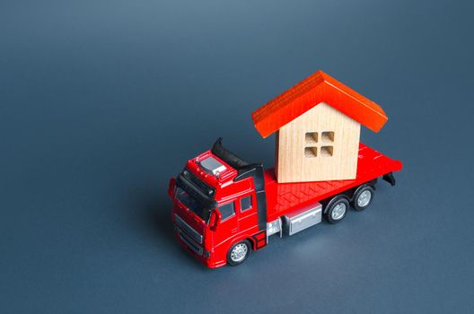 Truck transporting a house. Delivery services to another house. A moving company. Transportation of real estate. Resettlement program for new housing. Construction industry. Building insurance.