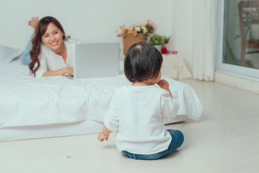 mother with laptop and her child on the bed in the morning