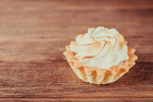 Delicious cupcake with whipped cream on a wooden background.