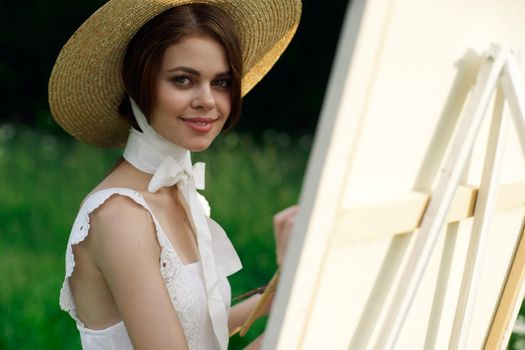 Woman in white dress artist easel painting nature landscape. High quality photo