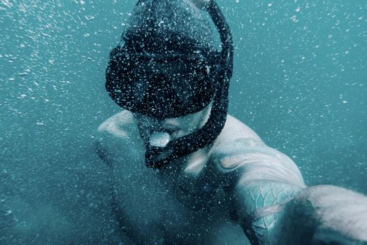 Freediver young man taking selfie portrait underwater, point of view.