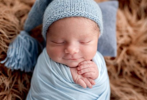 Smiling newborn holding knitted toy in tiny hands while sleeping