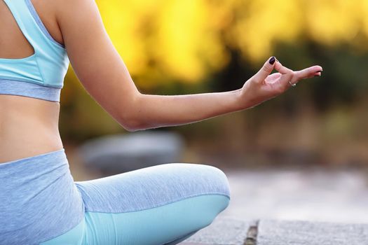 Close up of hand of young man sitting in lotus pose indoor. Light, zen and home yoga exercising concept with copyspace. Healthy lifestyle concept.