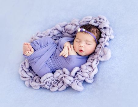 Cute newborn with floral rim wrapped in purple blanked
