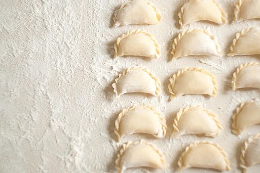 Dumplings (vareniki) with potatoes on white background - traditional Ukrainian food. Cooking raw dumplings with potatoes.