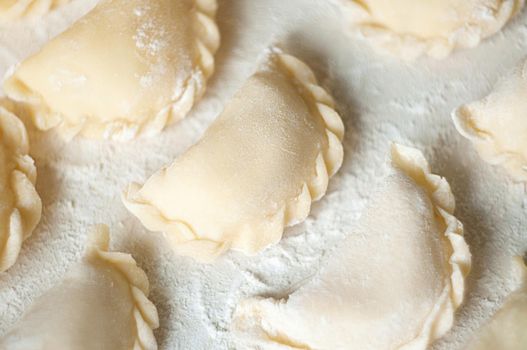 Dumplings (vareniki) with potatoes on white background - traditional Ukrainian food. Cooking raw dumplings with potatoes.