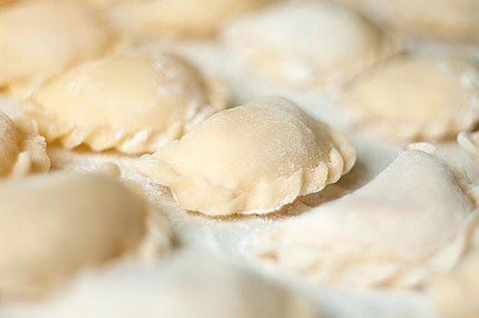 Dumplings (vareniki) with potatoes on white background - traditional Ukrainian food. Cooking raw dumplings with potatoes.