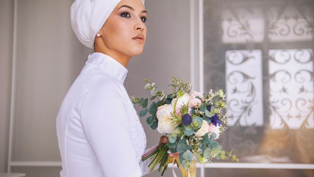 Young muslim bride with professional make up in wedding headdress with flowers bouquet, close up