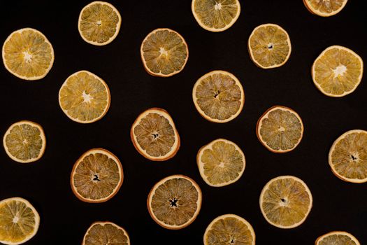 Repetitive pattern of dried oranges and tangerines at black background, view from the top, creative concept, eco life.