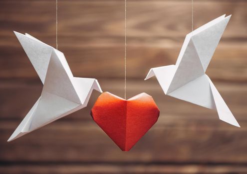 Two origami dove birds around red paper heart, symbol of love. Greeting card for Valentines day.