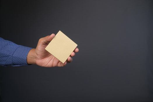 man hand hold a sticky note against gray background .