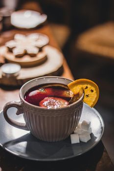 Red hot drink glintwein with spices, cinnamon, anise, fruits, brown sugar on an old wooden table. New Year and Christmas holidays concept. Mulled wine and glintwein