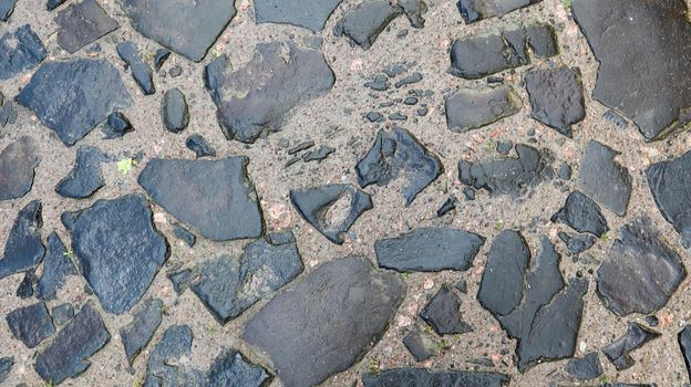 Closeup background texture of old wet pavement. An old cobblestone road for your background. Copy space. Flat lay.