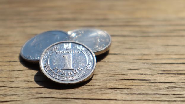 One new 2018 hryvnia coin on a wooden background. Ukrainian money.
