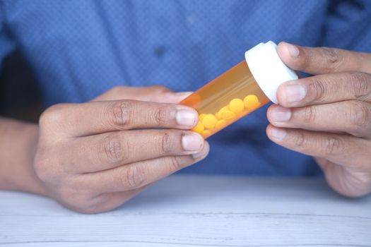 young man hand holding medicine pill container white sited .