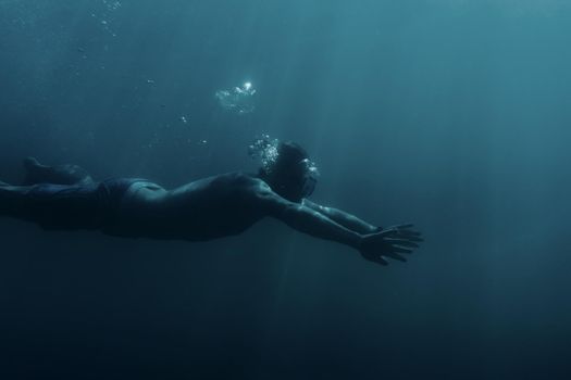 Freediver sporty young man swimming underwater, breaststroke.