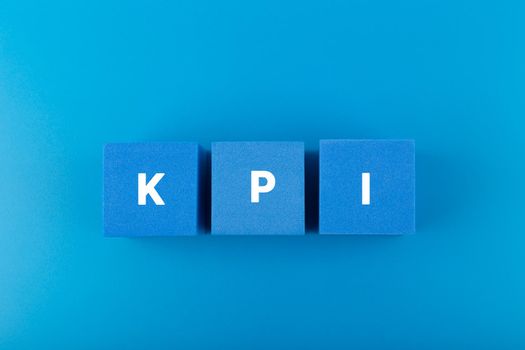 Minimal modern business KPI concept. KPI letters on blue toy cubes in a row against dark blue background with copy space. High quality photo