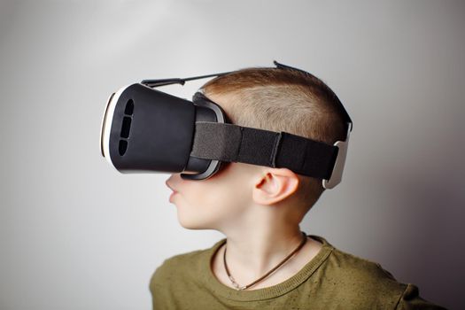 Boy playing mobile game app on device virtual reality glasses on white background. Boy action and using in virtual headset, VR box for use with smart phone. Contemporary technology concept, close up