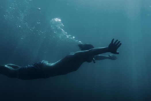 Freediver young man swimming underwater and using breaststroke technique.