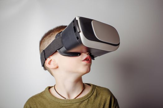 Boy playing mobile game app on device virtual reality glasses on white background. Boy action and using in virtual headset, VR box for use with smart phone. Contemporary technology concept, close up