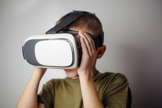 Boy playing mobile game app on device virtual reality glasses on white background. Boy action and using in virtual headset, VR box for use with smart phone. Contemporary technology concept, close up