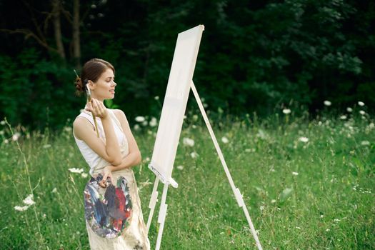 woman artist with palette of paints drawing easel nature hobby. High quality photo