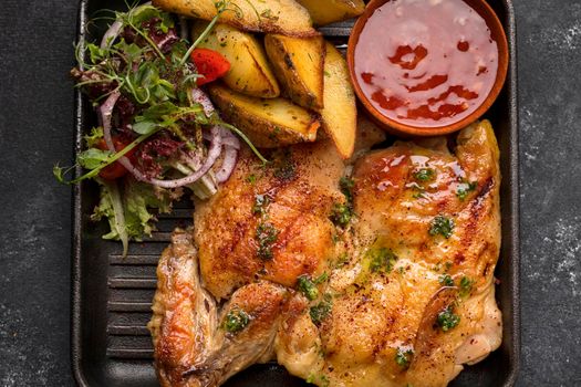 Fried chicken with a crispy crust, salad, potatoes and sauce, in a skillet